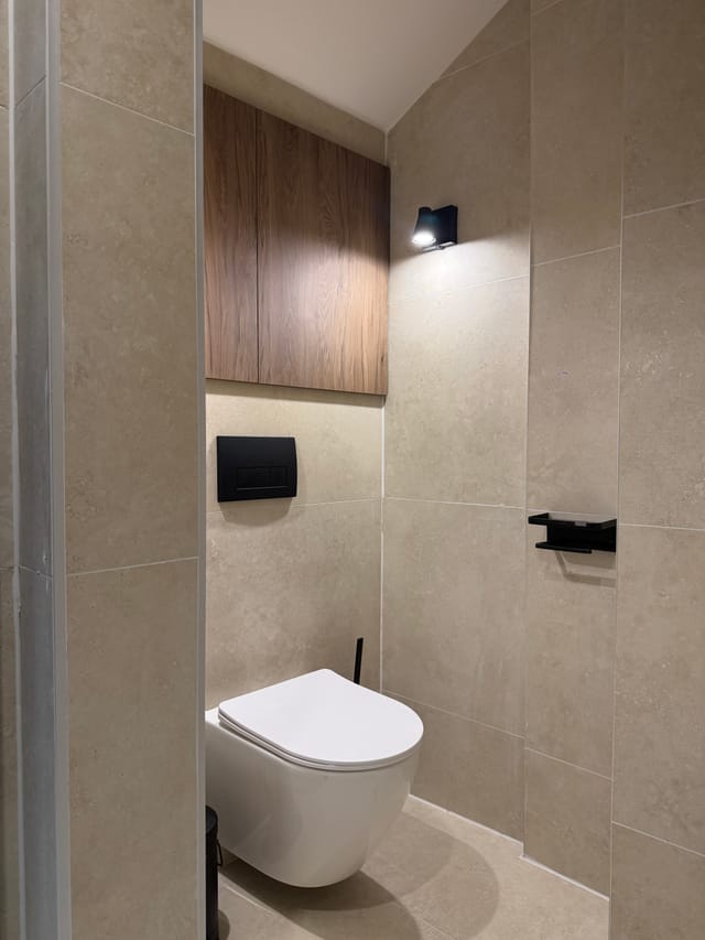 Tiled bathroom with wall-hung toilet and storage