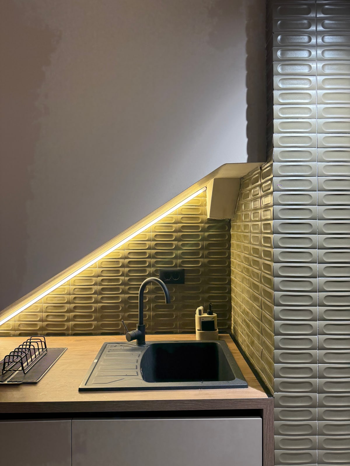 Kitchen sink beneath illuminated olive tiles