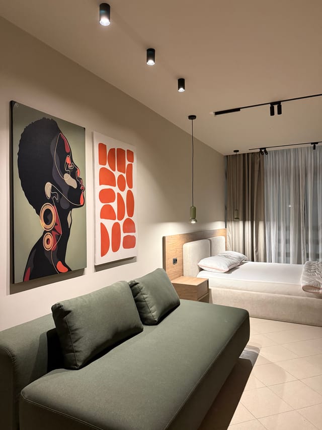 Open-plan studio with sofa and bed beside the window