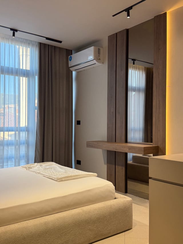 Bed beside the window with dressing mirror and air conditioning